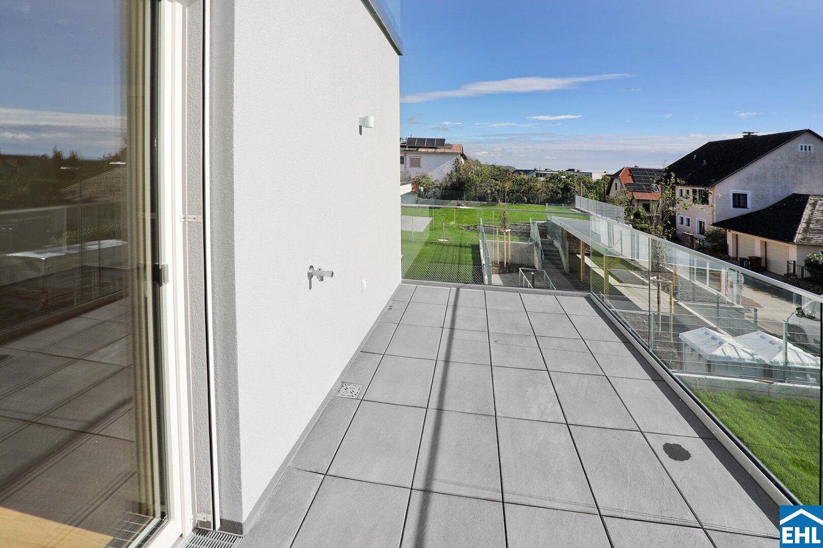 Geräumiger Balkon mit Fliesenboden und Glasgeländer, ideal zum Entspannen im Freien.