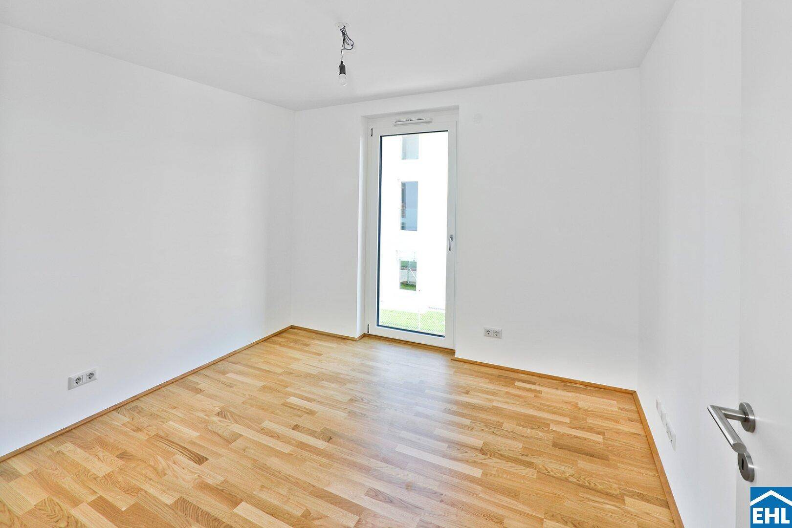 Kleiner, heller Raum mit Holzboden und Zugang zu einem Außenbereich.