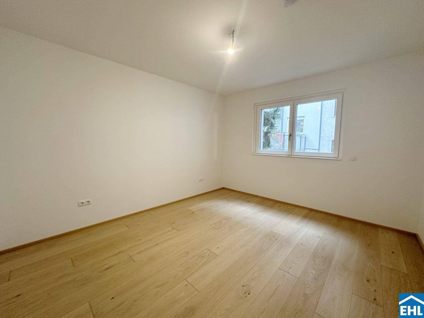 Helles Schlafzimmer mit neuem Holzboden und einem Fenster, das viel Tageslicht hereinlässt.
