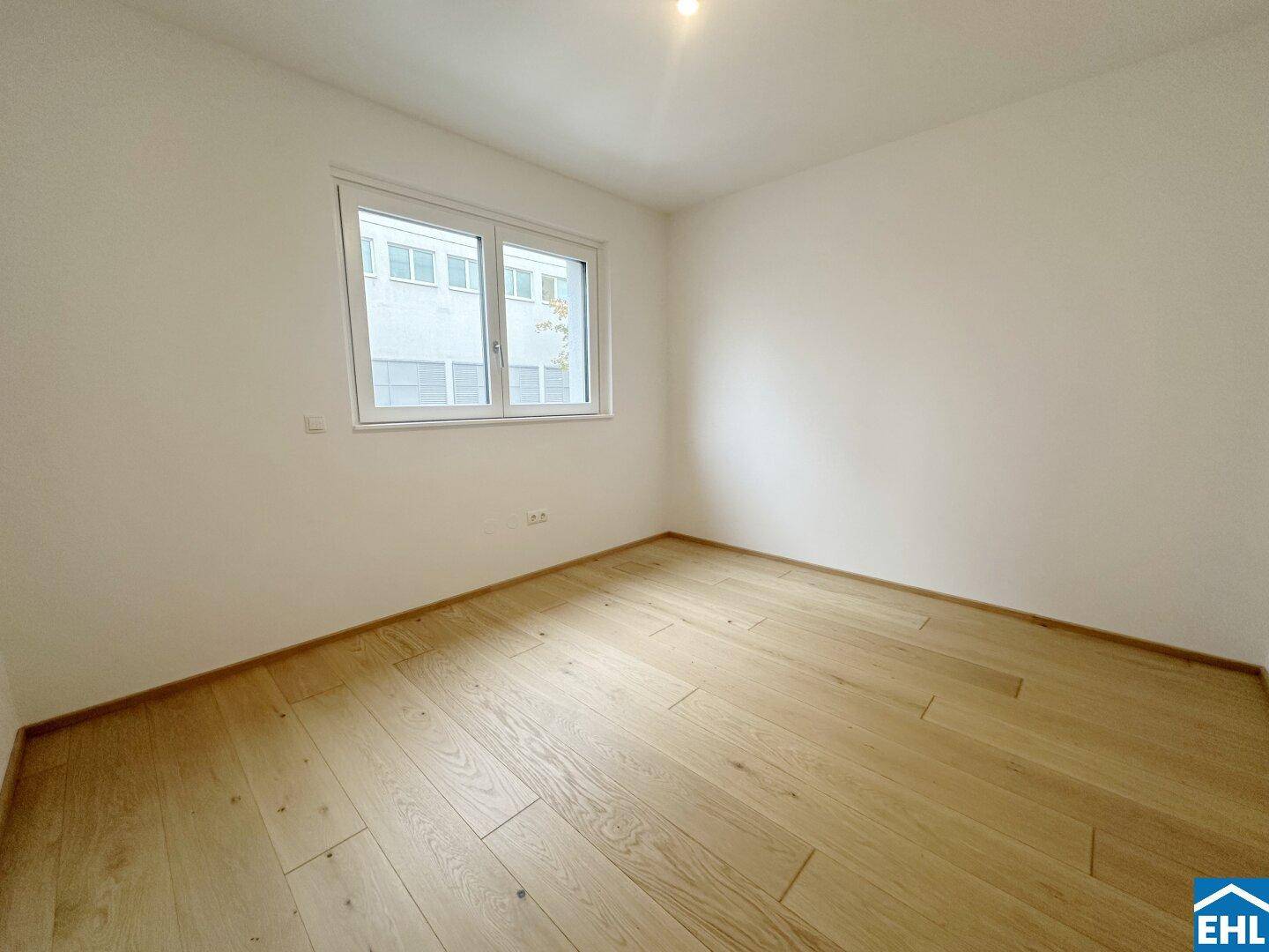 Geräumiges Schlafzimmer mit hellem Parkettboden und großen Fenstern für optimale Belichtung.