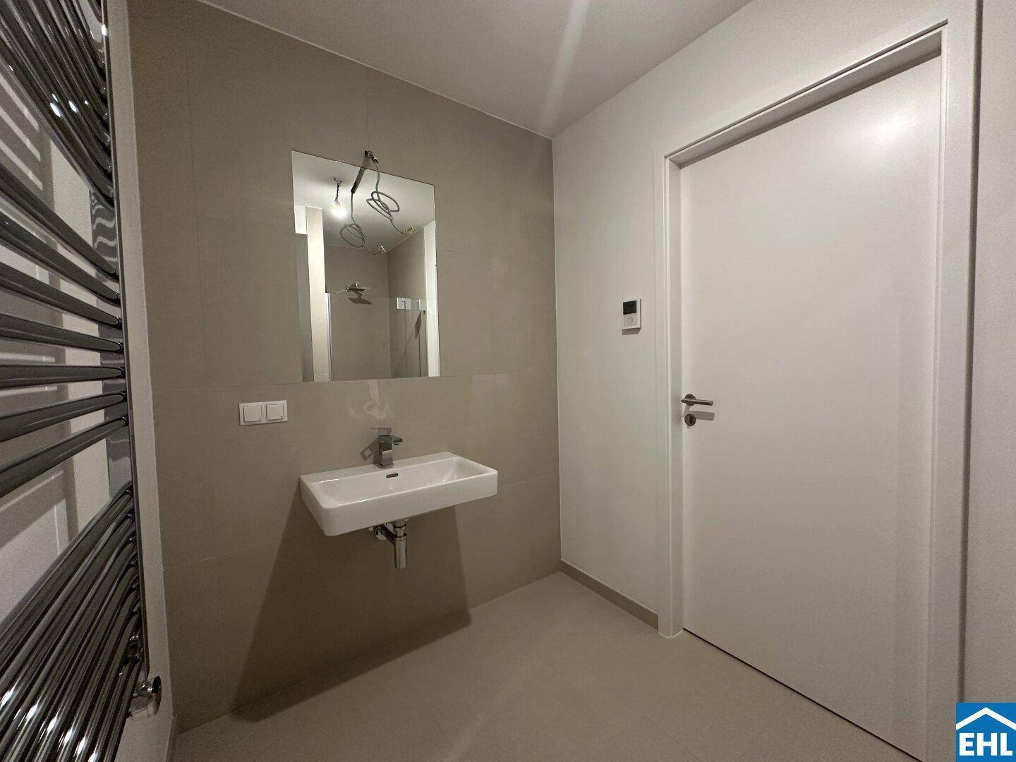 Modernes Badezimmer mit Einzelwaschbecken, Fliesenwänden und einem praktischen Handtuchheizkörper.