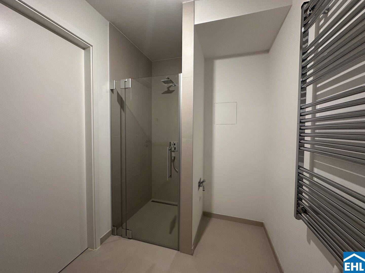 Zeitgemäßes Badezimmer mit ebenerdiger Dusche, Glasabtrennung und einem beheizten Handtuchhalter.