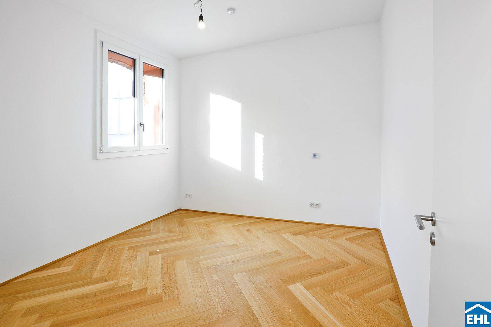 Ruhiges, helles Zimmer mit Fischgrätparkett und einem großen Fenster.