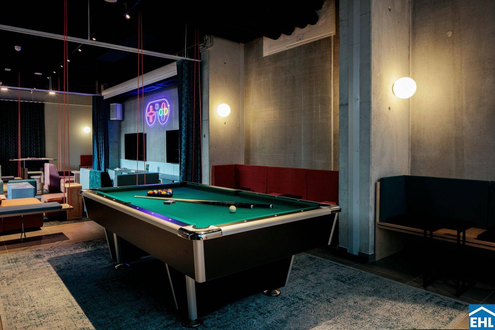 Unterhaltsamer Spielbereich mit Billardtisch, Sitzgelegenheiten und moderner Beleuchtung.