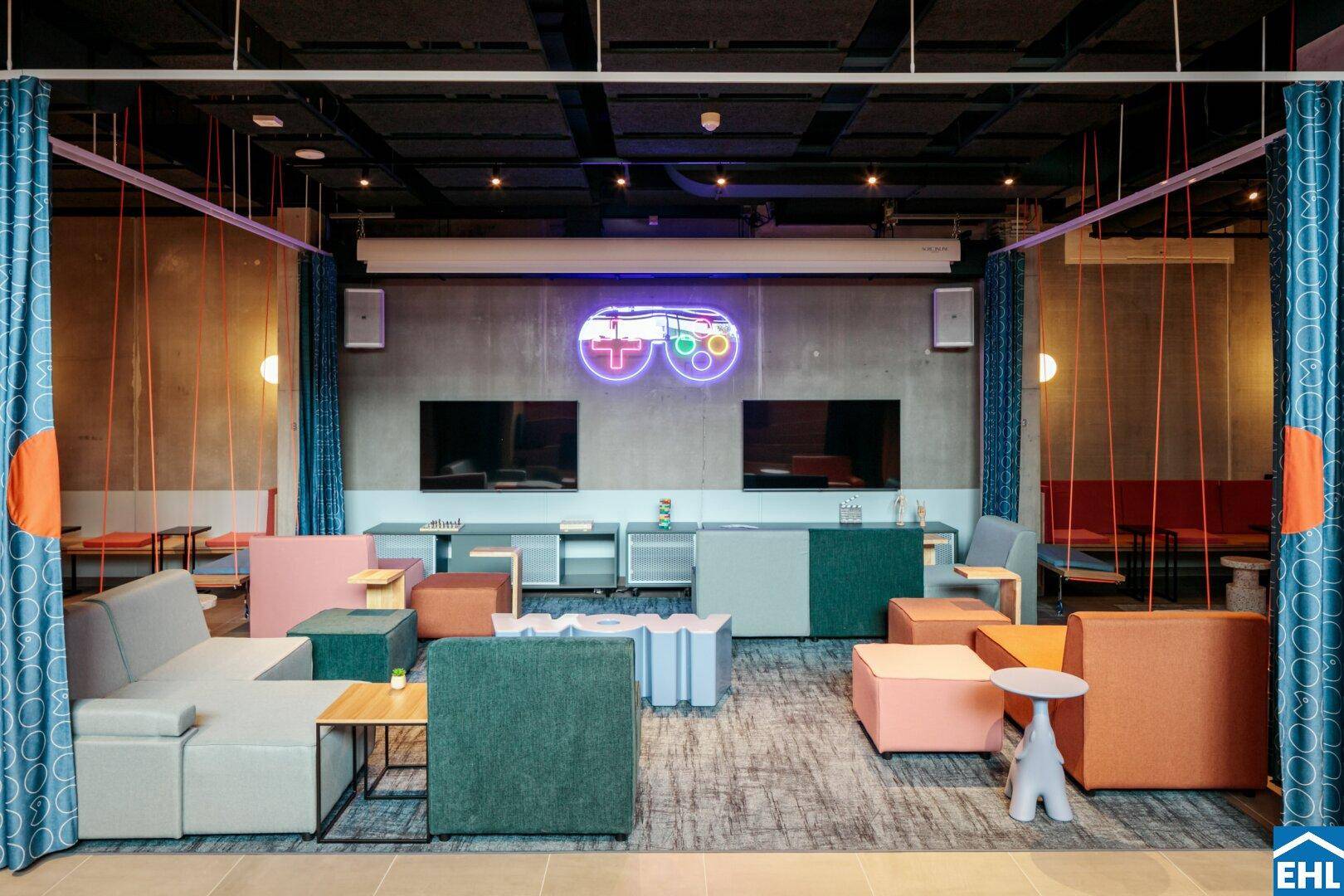 Lebhafter Spielbereich mit bequemen Sofas, Fernsehern und Neonlicht-Dekoration.