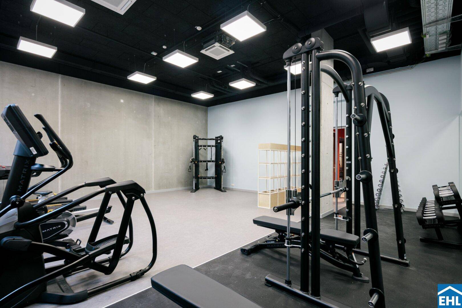 Gut ausgestatteter Fitnessraum mit verschiedenen Trainingsgeräten und viel Platz.