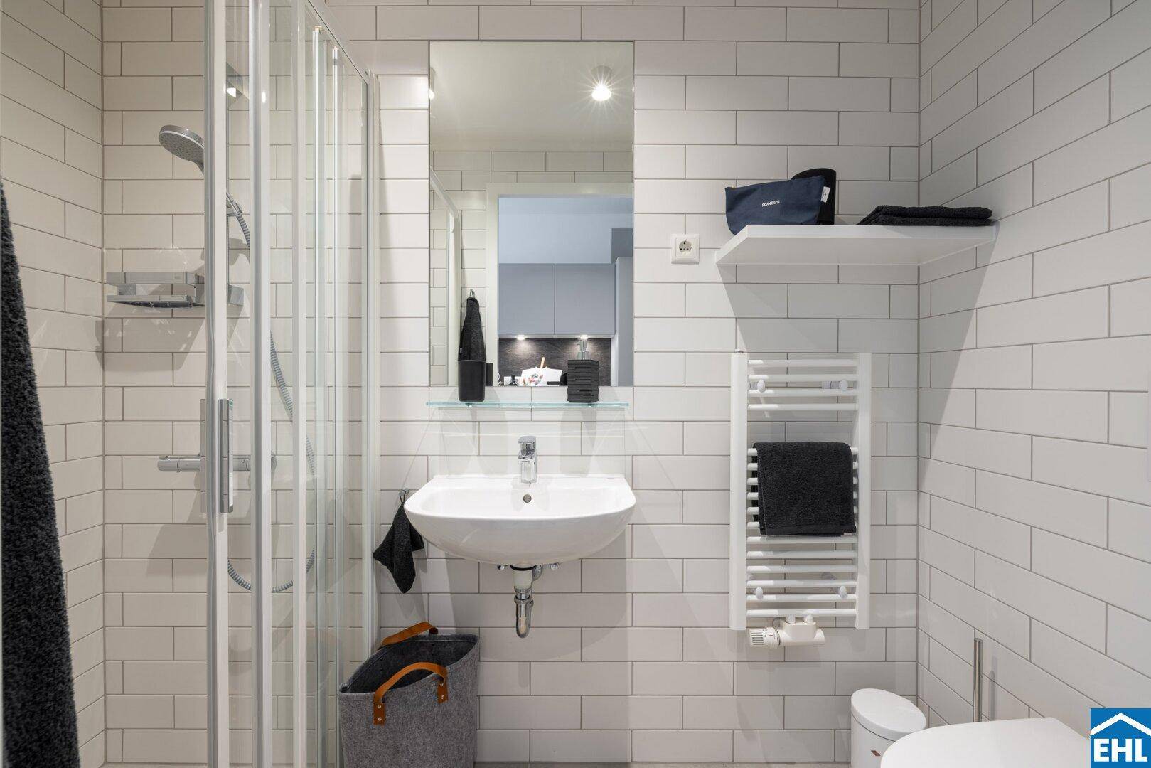 Modernes Badezimmer mit weiß gefliesten Wänden, Dusche und beheiztem Handtuchhalter.
