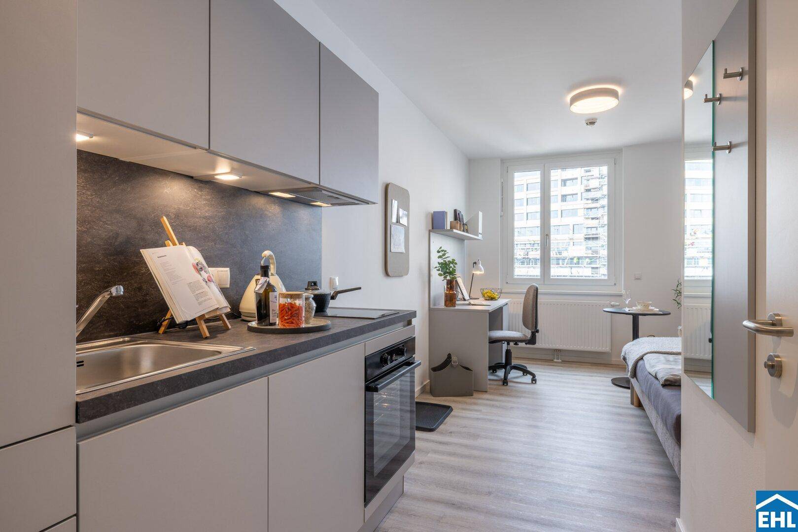 Moderne Küchenzeile in einem Studio-Apartment mit Blick auf den Wohnbereich.