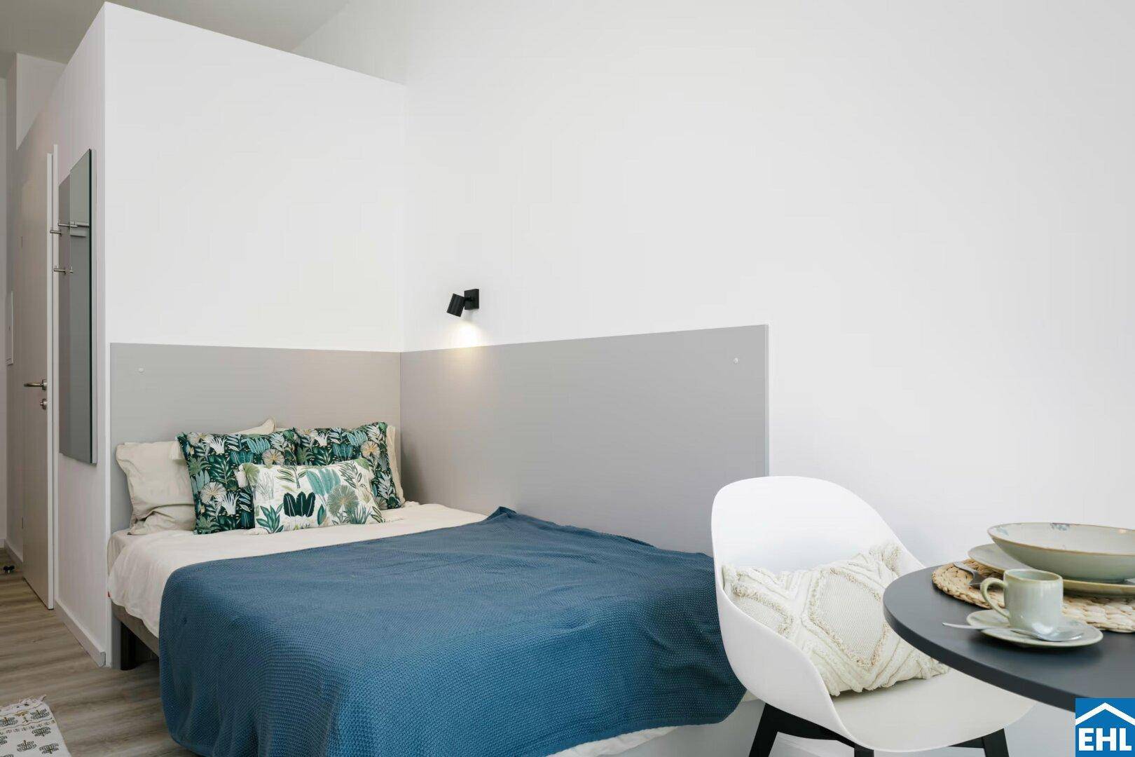 Gemütlicher Schlafbereich im Studio-Apartment mit modernem Bett und dekorativen Kissen.