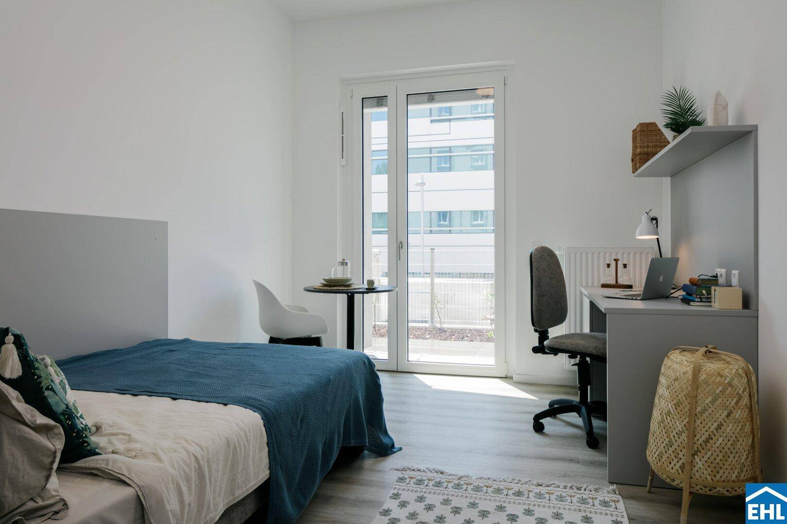 Schlaf- und Arbeitsbereich im Studio mit großem Fenster und Zugang zu einem kleinen Balkon.