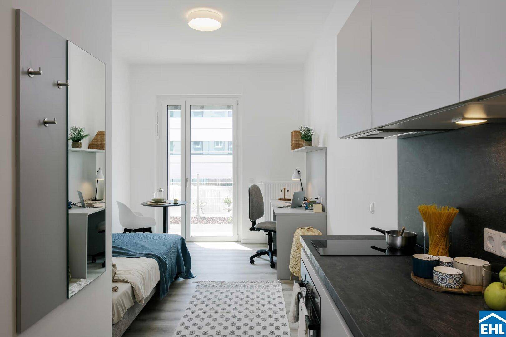 Heller Studio-Wohnbereich mit Zugang zum Balkon, Schreibtisch und integrierter Küchenzeile.
