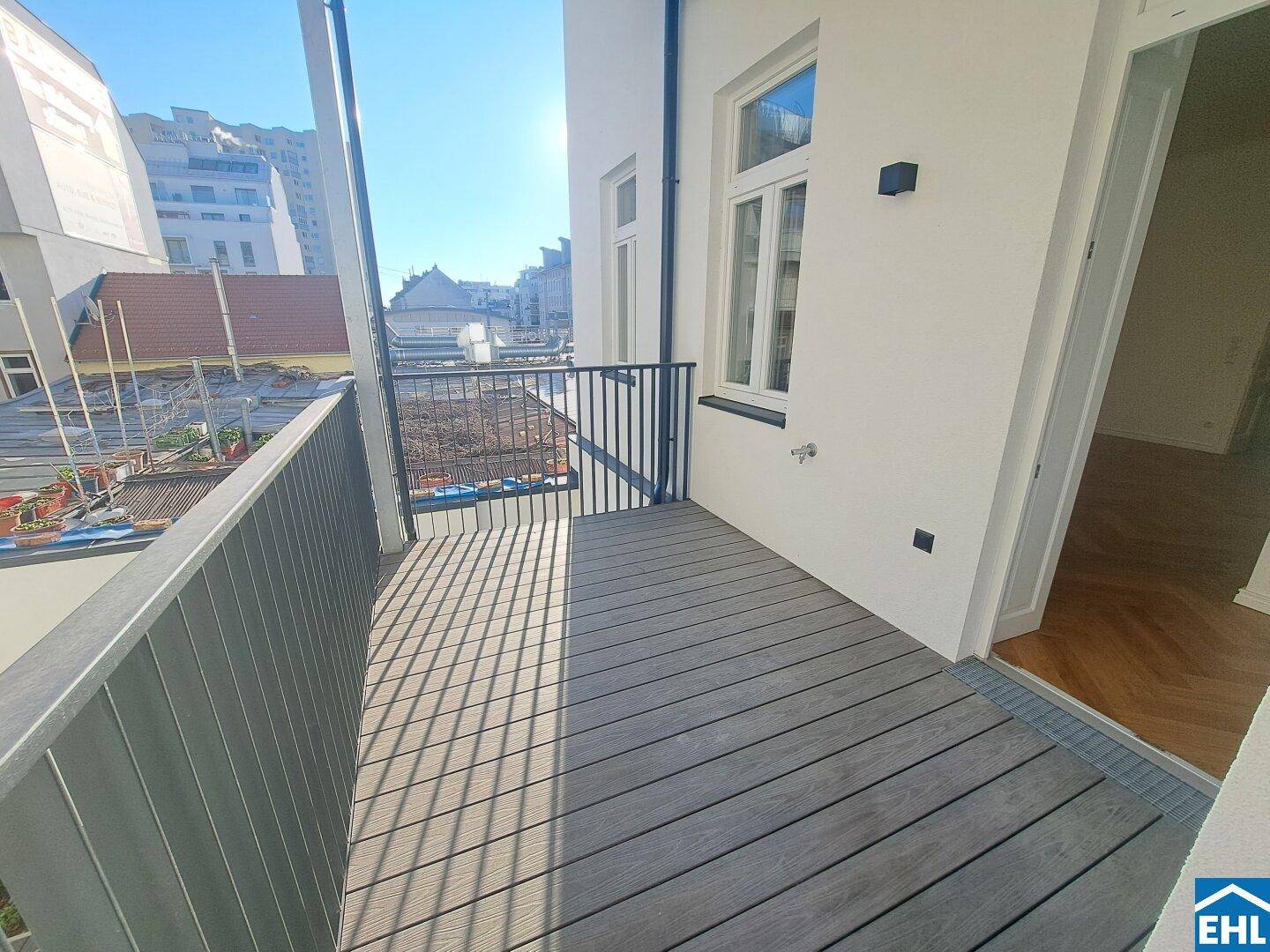 Sonniger Balkon mit modernen Holzdielen und Blick auf die städtische Umgebung.