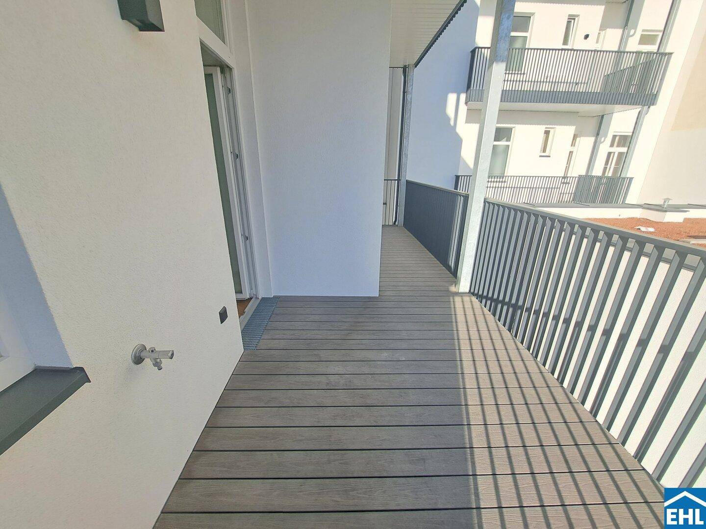 Langer, schmaler Balkon mit Holzdielenboden und Metallgeländer, bietet einen Blick auf die Umgebung.