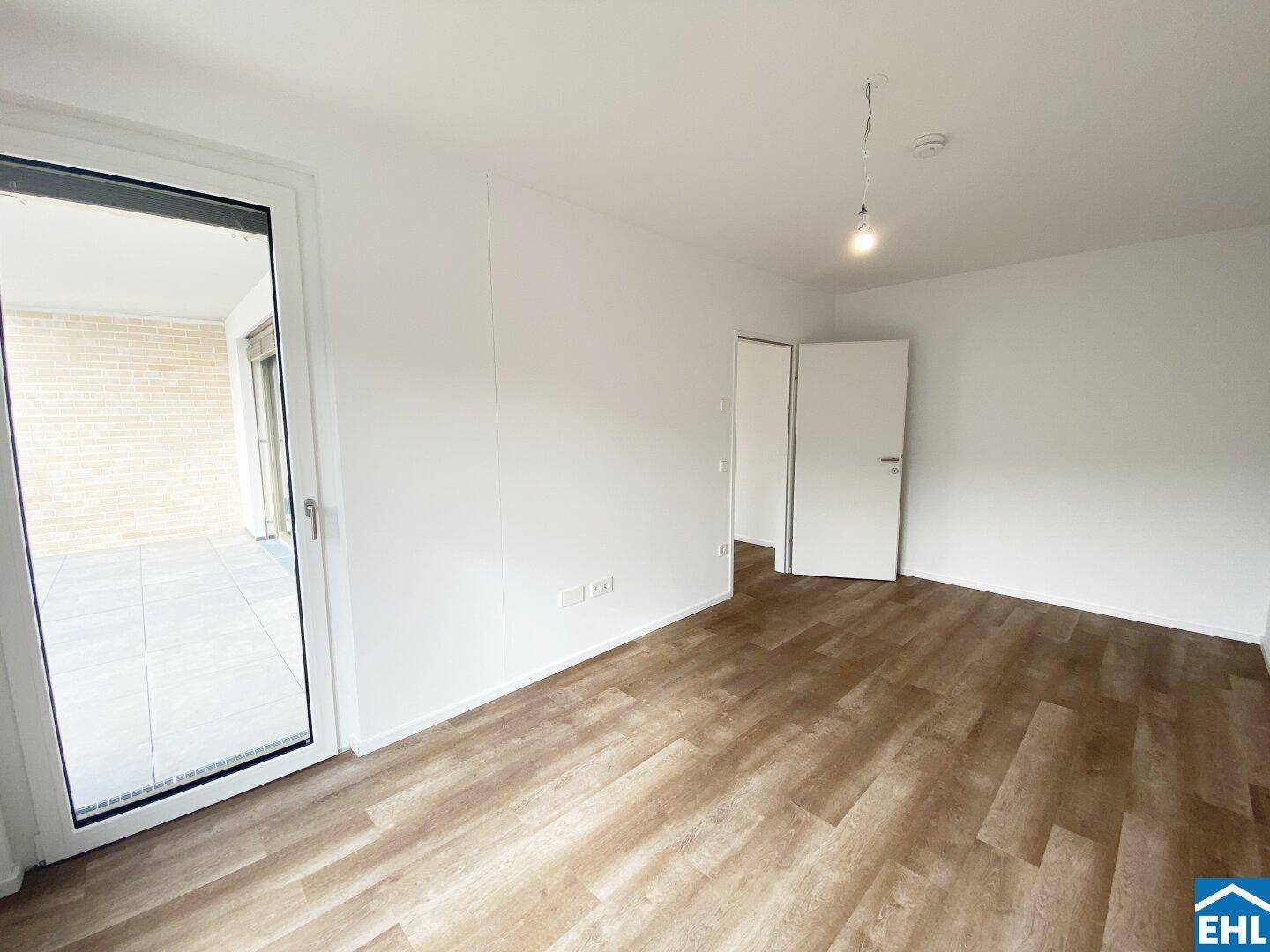 Geräumiges Zimmer mit hellem Laminatboden und direktem Zugang zur Terrasse.