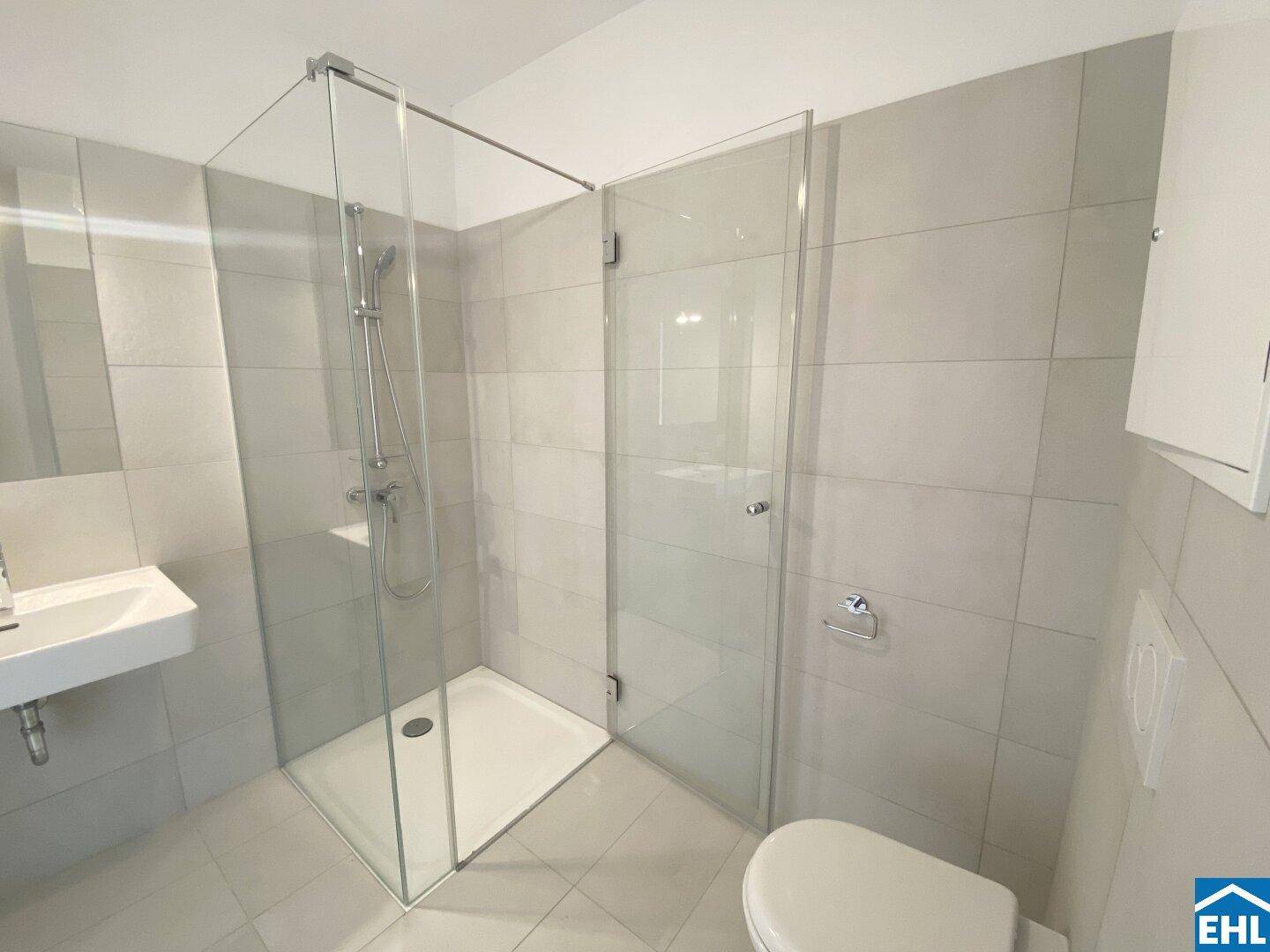 Modernes Badezimmer mit ebenerdiger Dusche, Wand-WC und großformatigen Fliesen.