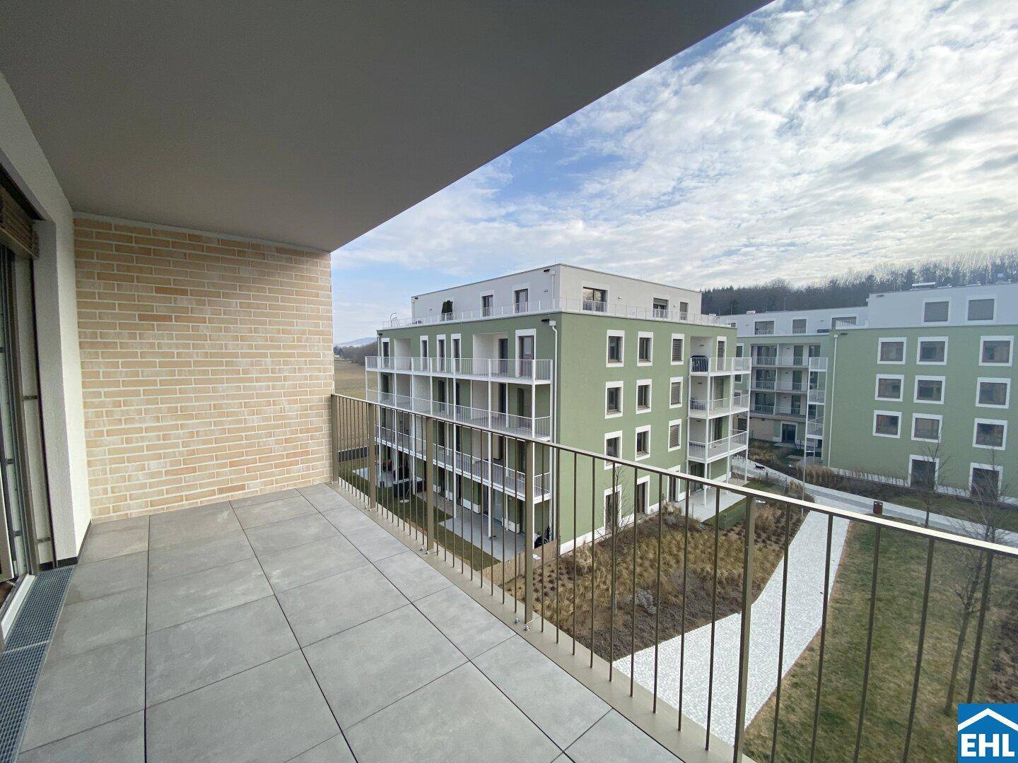 Breiter Balkon mit Fliesenboden und weitem Blick über die Umgebung und andere Gebäude.