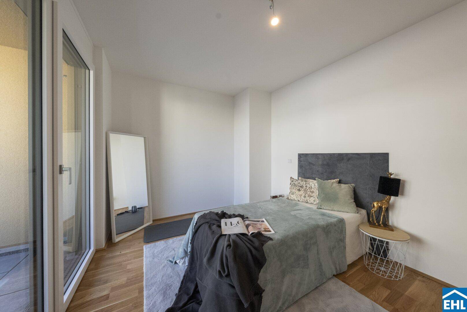 Helles Schlafzimmer mit Holzboden, modernem Bett und Zugang zu einem Balkon.