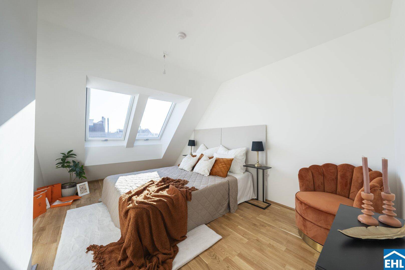 Schlafzimmer im Dachgeschoss mit Holzboden, gemütlicher Einrichtung und zwei Dachfenstern.