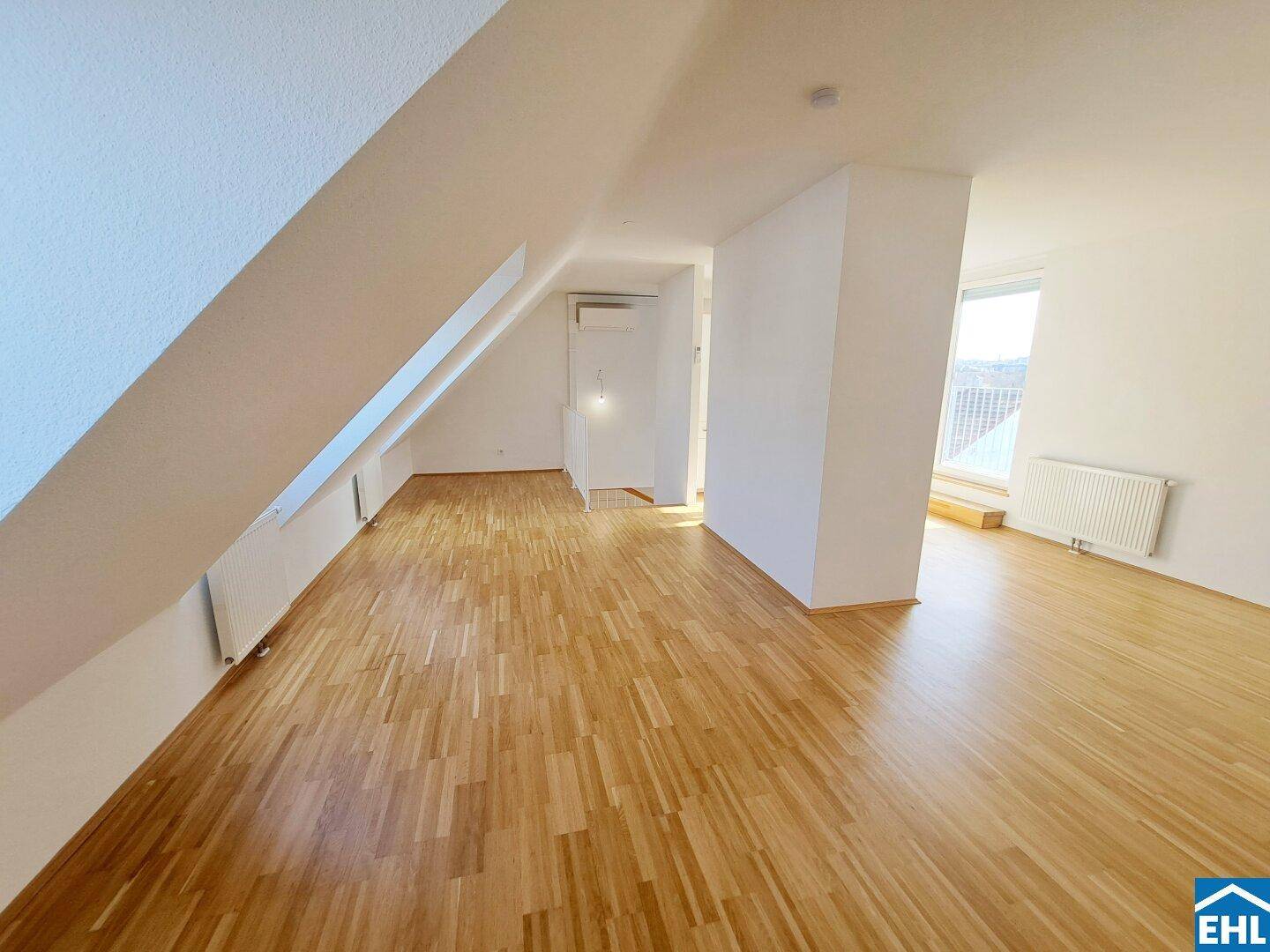 Helles Dachgeschosszimmer mit Holzboden und schrägen Wänden, bereit für individuelle Gestaltung.