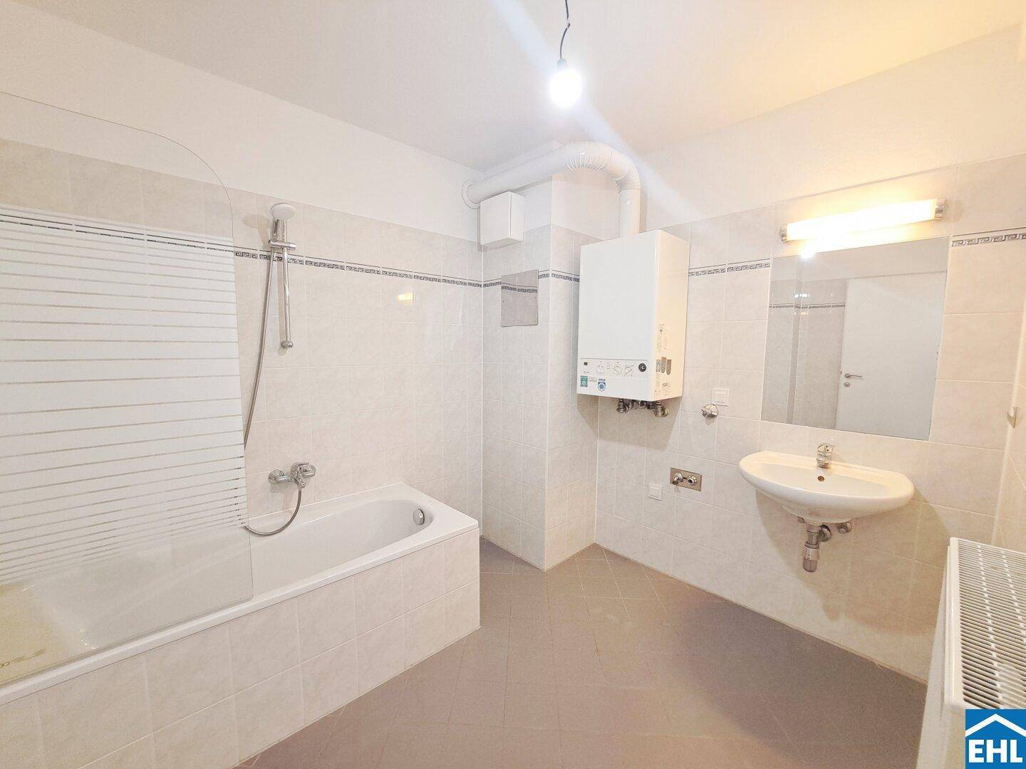 Funktionales Badezimmer mit Badewanne, Waschbecken und Wandfliesen in hellem Design.