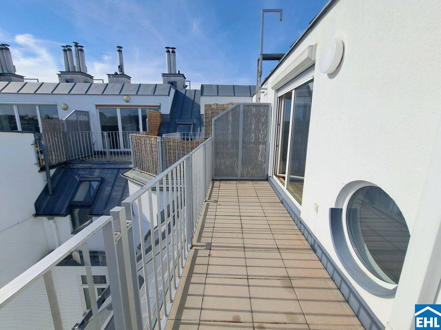 Lange Dachterrasse mit Metallgeländer und weitem Blick über die umliegenden Gebäude.