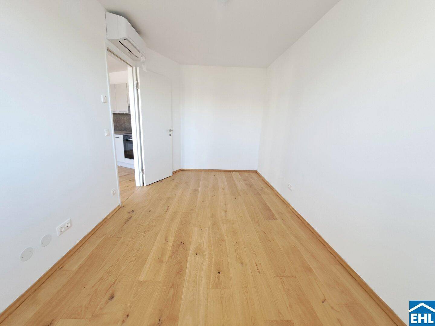 Helles Zimmer mit Parkettboden und Zugang zu einem weiteren Raum, ideal als Schlafzimmer.