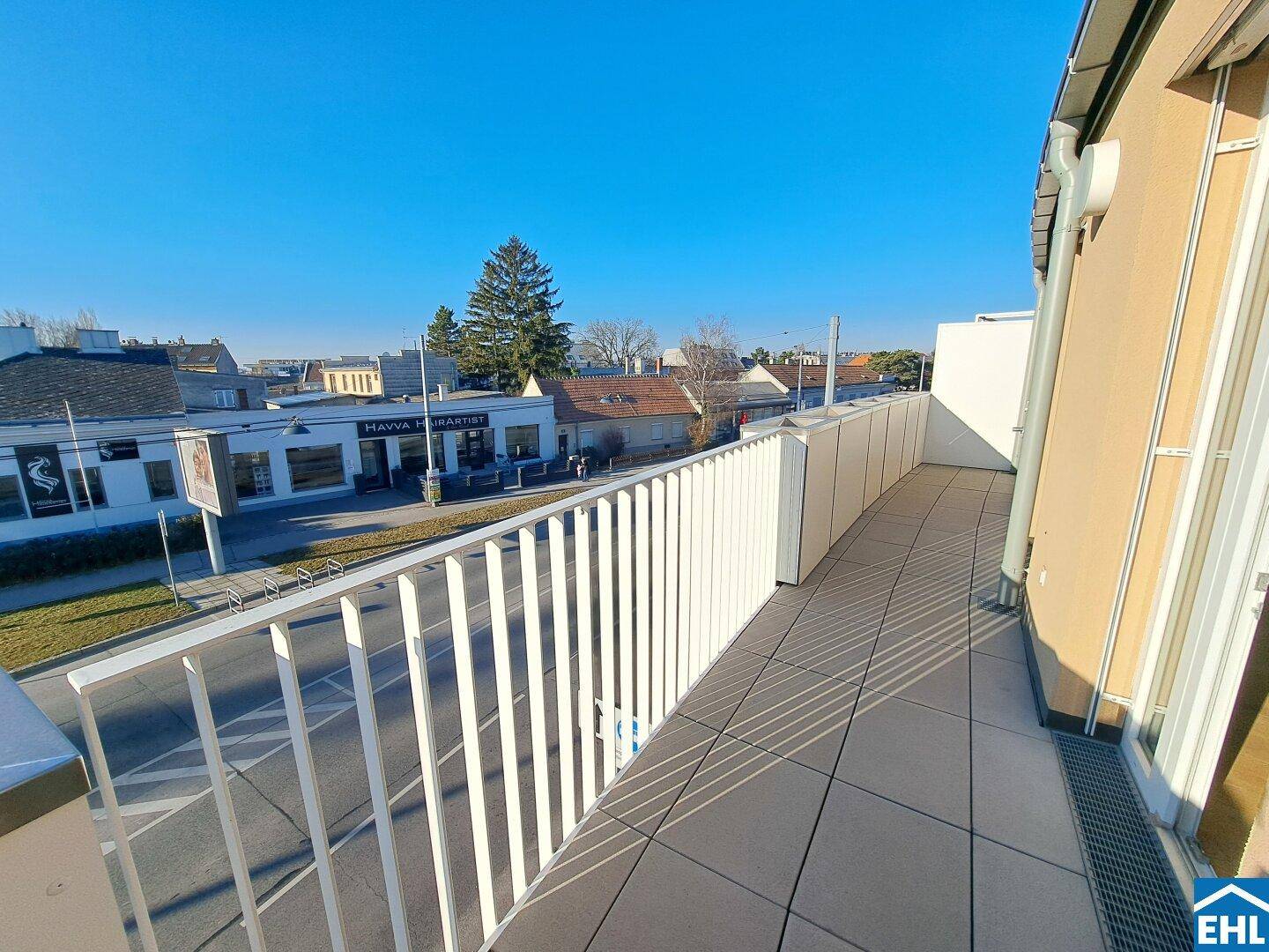 Langer Balkon mit Fliesenboden und Blick auf die umliegende Nachbarschaft.
