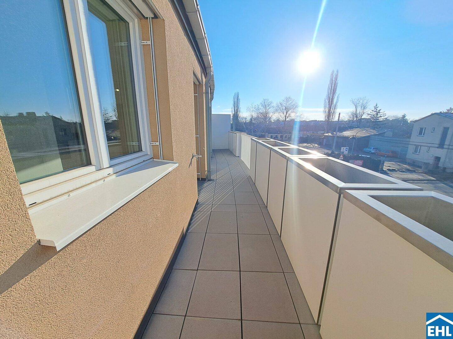 Sonniger Balkon mit Fliesenboden und seitlichem Blick auf die Umgebung.