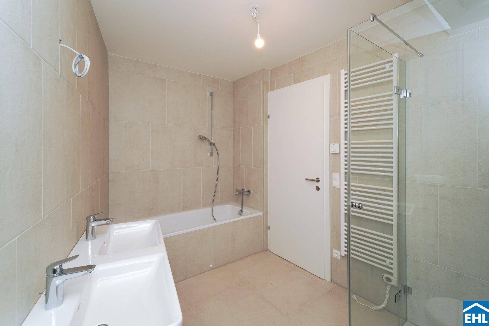 Modernes Badezimmer mit Doppelwaschbecken, Badewanne und beheiztem Handtuchhalter.