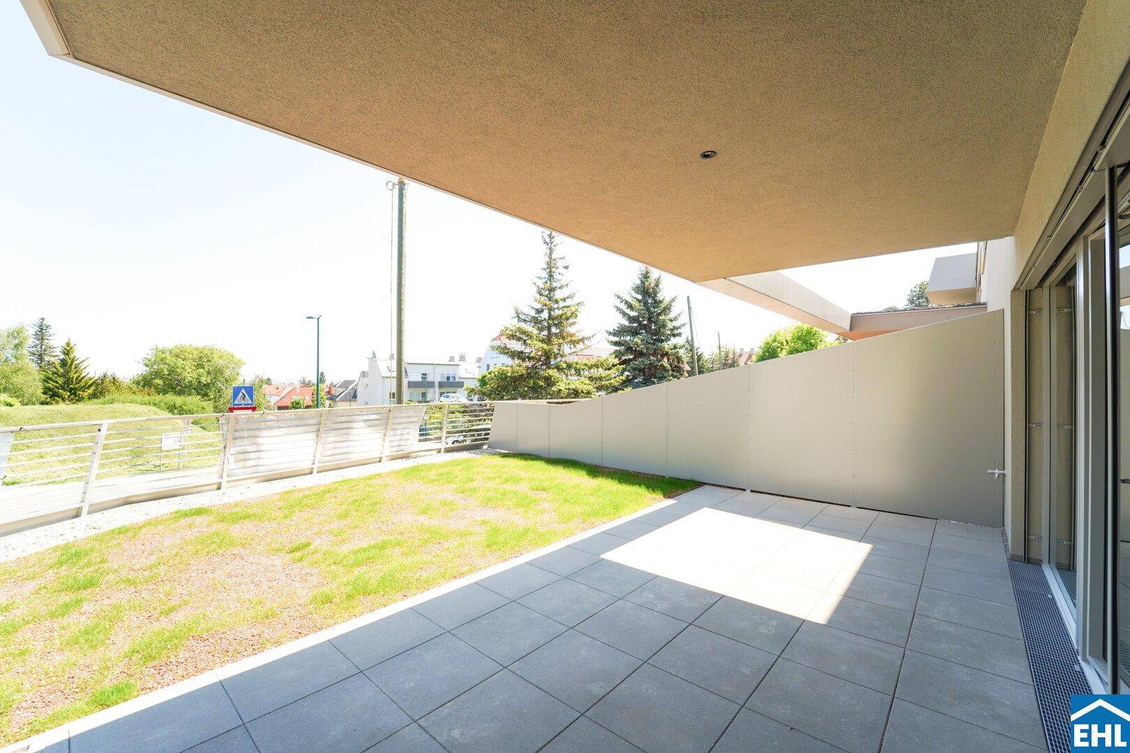 Überdachte Terrasse mit Fliesenboden und privatem Gartenbereich, umgeben von einer Mauer.