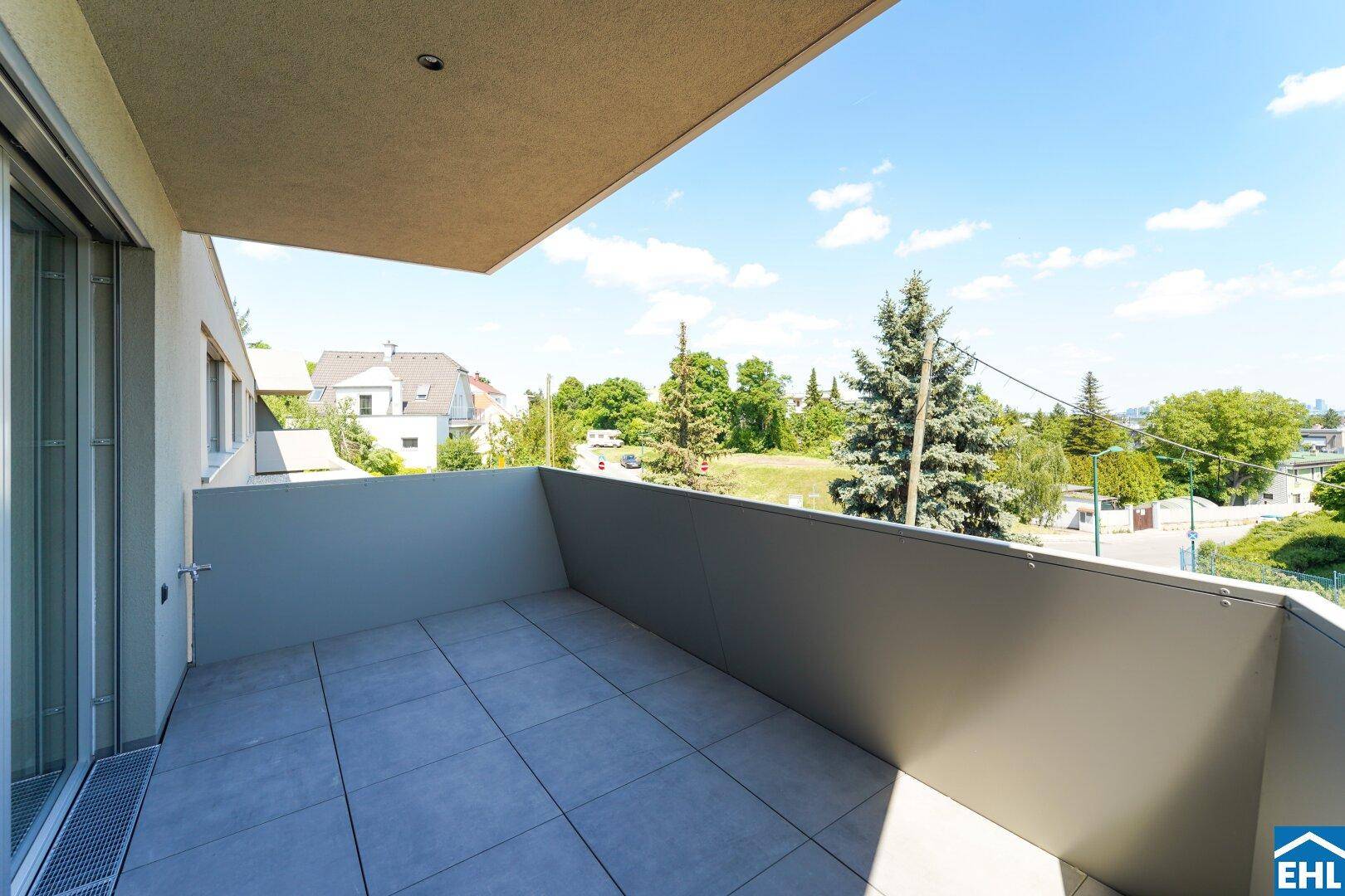 Geräumiger Balkon mit Fliesenboden und weitem Blick ins Grüne und die Umgebung.