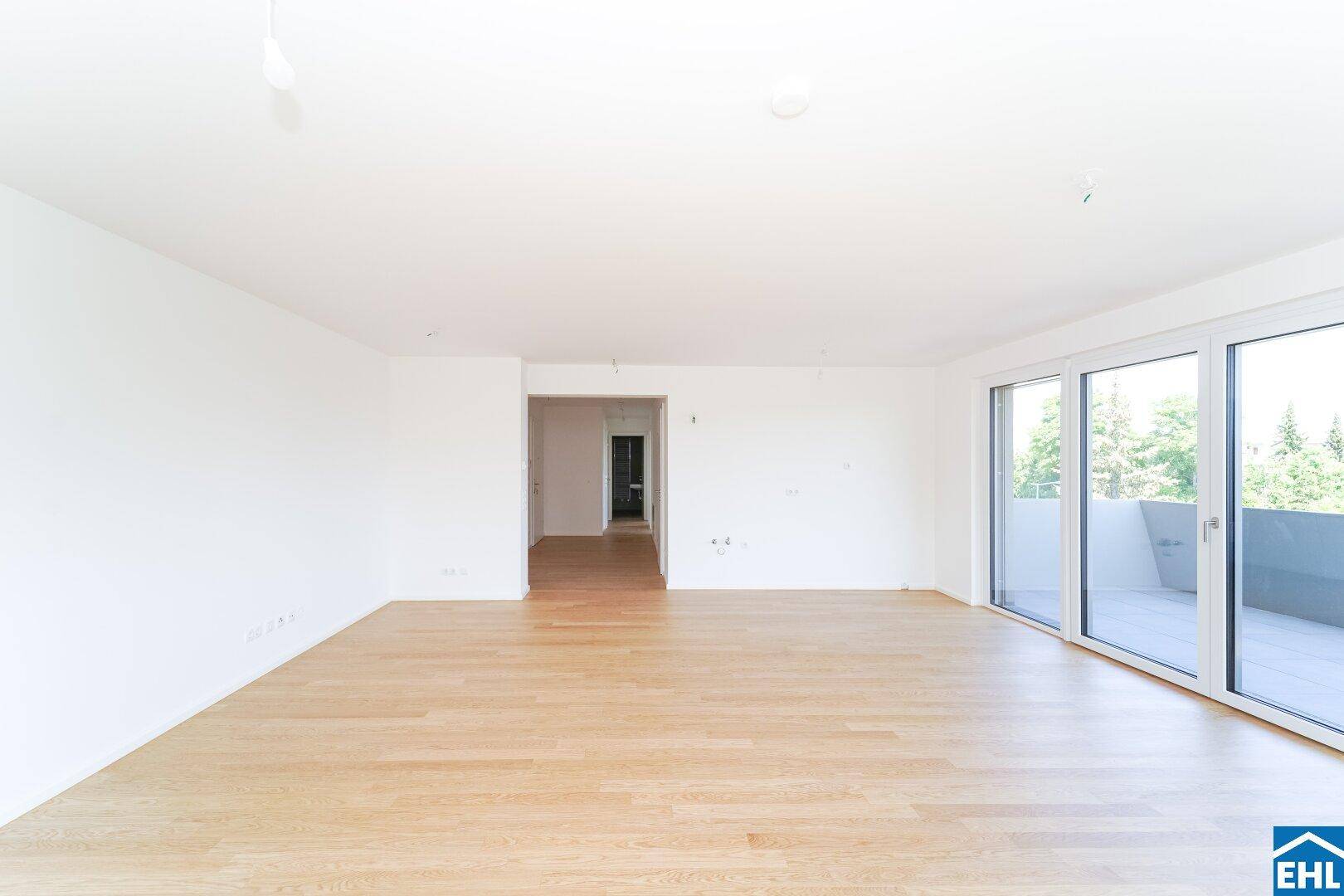 Geräumiges Wohnzimmer mit hellem Parkettboden und offenem Zugang zum Flur.