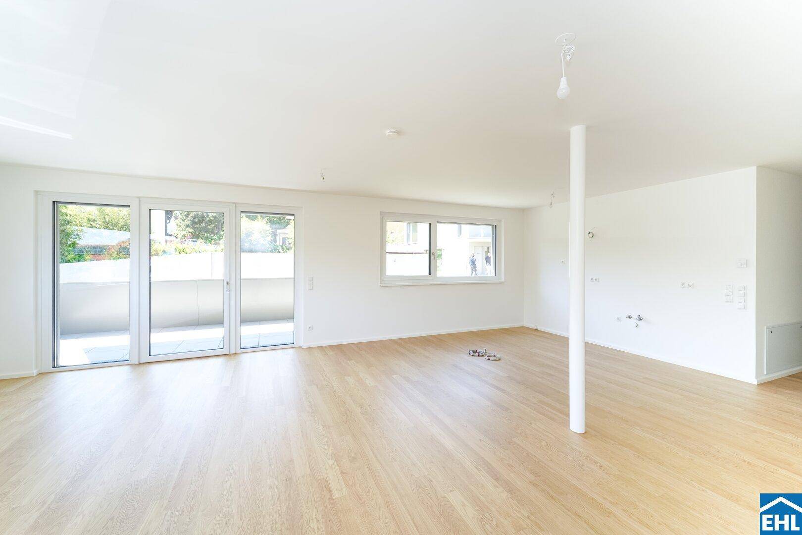 Geräumiger, heller Wohnbereich mit Holzboden und Zugang zu einem Balkon.