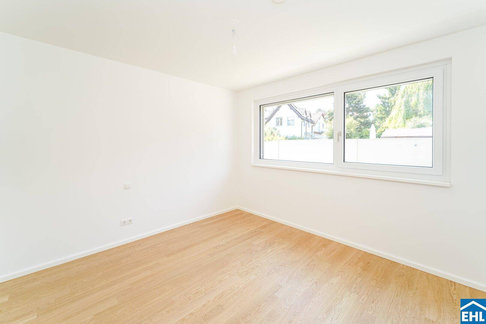 Geräumiges Zimmer mit Parkettboden und Blick auf die umliegende Wohngegend.