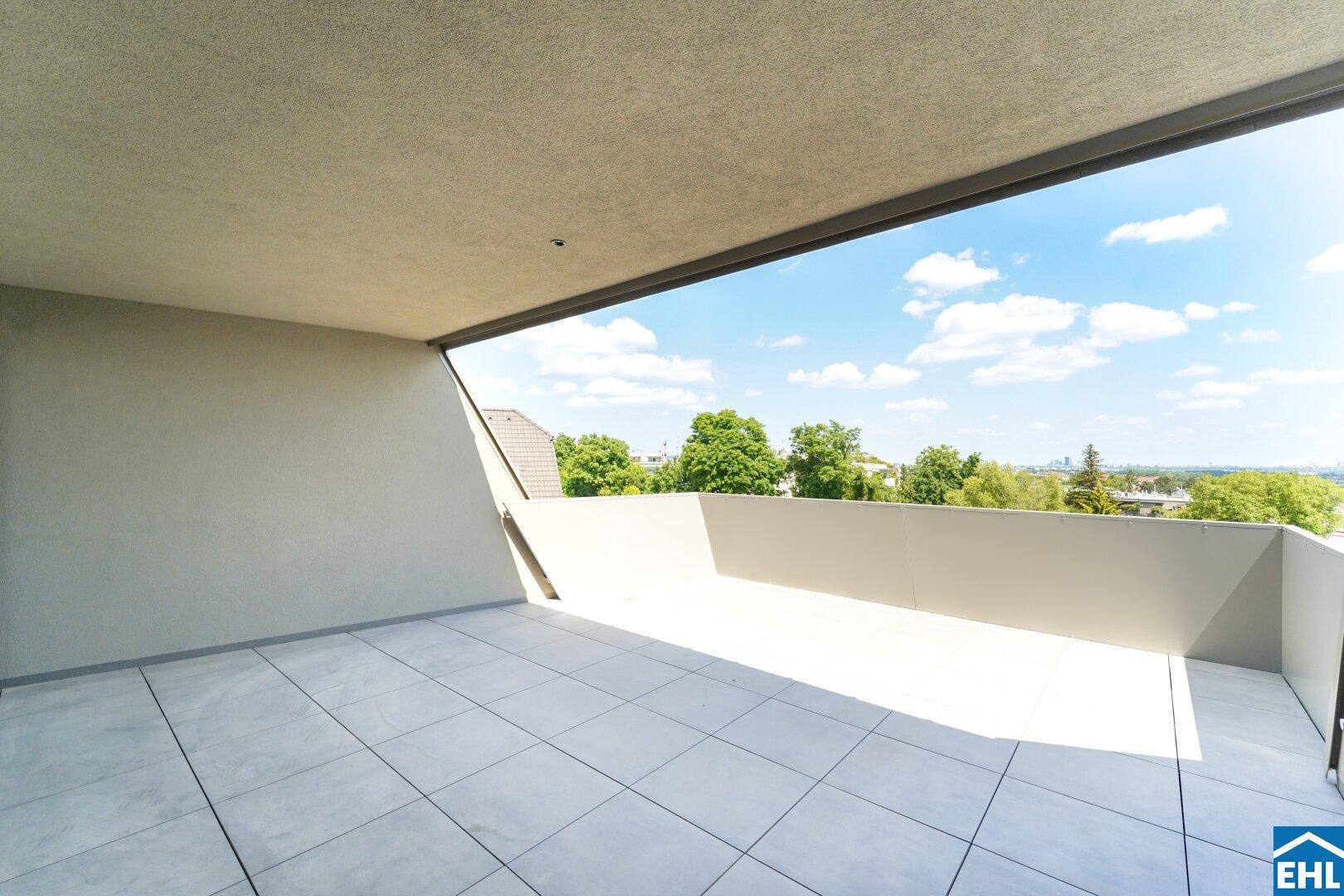 Geräumige, geflieste Terrasse mit weitem Blick ins Grüne und teilweise überdachtem Bereich.