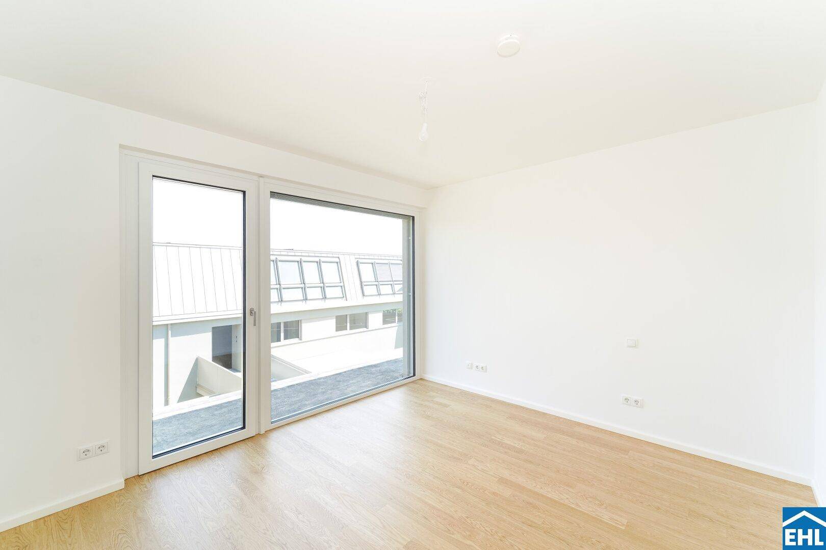 Geräumiger Raum mit Parkettboden und viel Tageslicht durch die große Fensterfront.