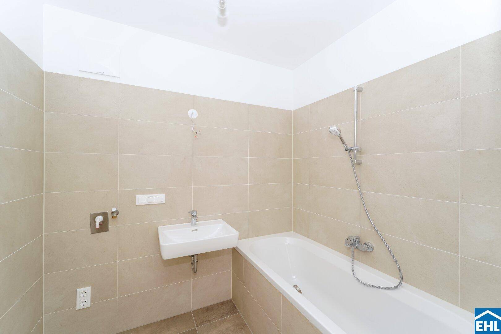 Modernes Badezimmer mit beigefarbenen Fliesen, Badewanne und wandmontiertem Waschbecken.