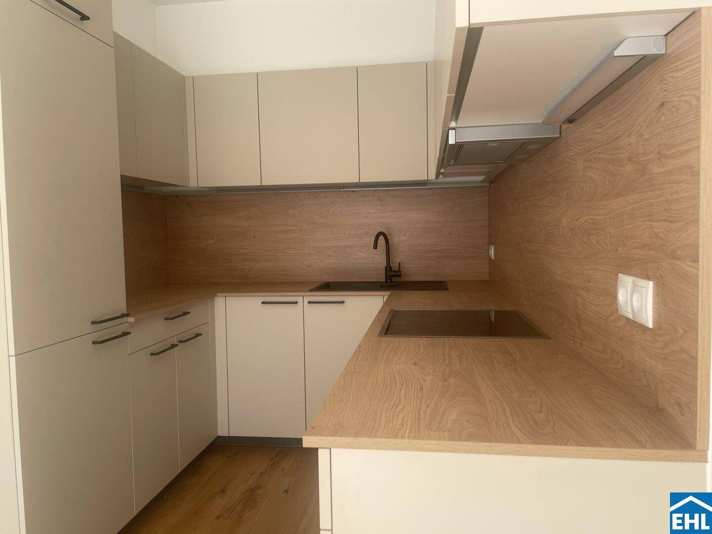 Moderne Einbauküche in Beige- und Holztönen mit Induktionskochfeld, Dunstabzugshaube und viel Stauraum.
