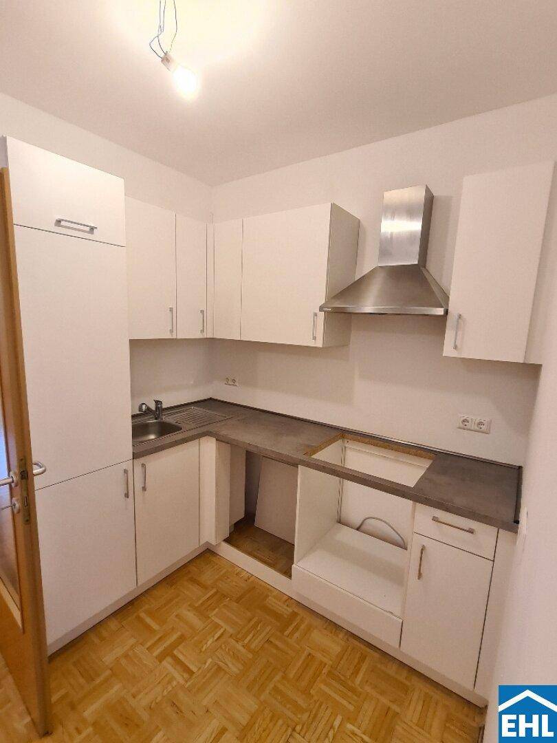 Helle Küche mit weißen Schränken, Spüle und Dunstabzugshaube, bereit für die Installation weiterer Geräte.