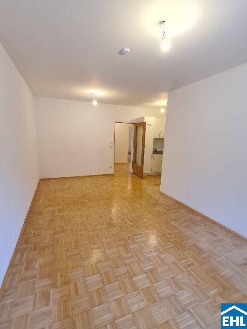 Geräumiger, heller Wohnbereich mit klassischem Parkettboden und Zugang zu weiteren Räumen.