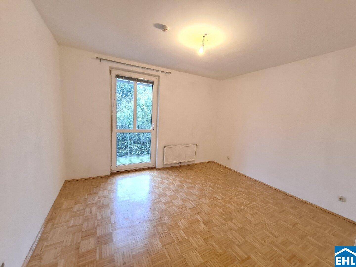Helles Zimmer mit Parkettboden, großem Fenster und Heizkörper, ideal als Schlaf- oder Arbeitszimmer.