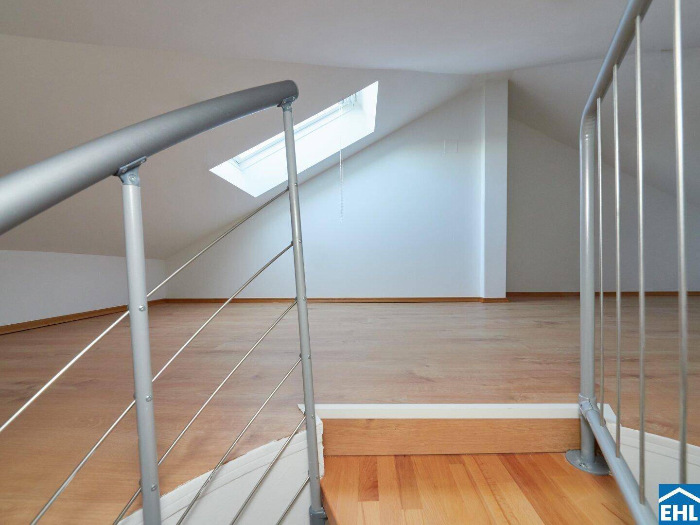 Dachgeschossbereich mit Laminatboden, Dachfenster und modernem Treppengeländer, das zum unteren Bereich führt.
