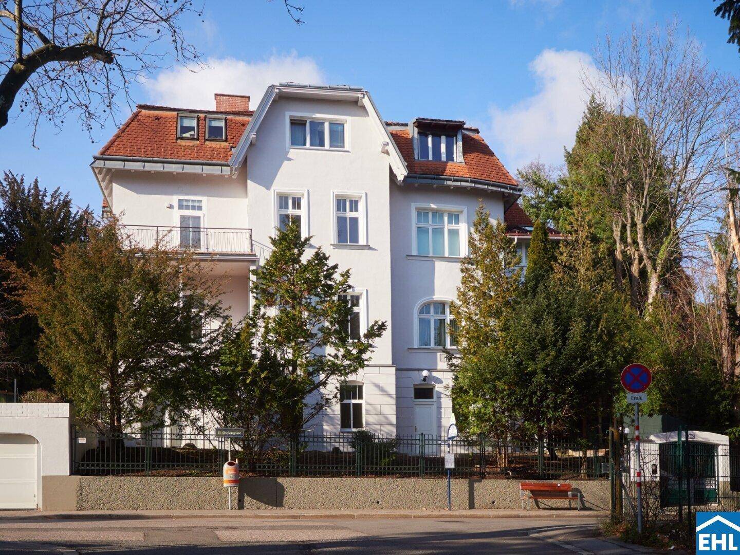 Elegante Stadtvilla mit klassischer Architektur, Balkonen und gepflegter Fassade, umgeben von Grün.