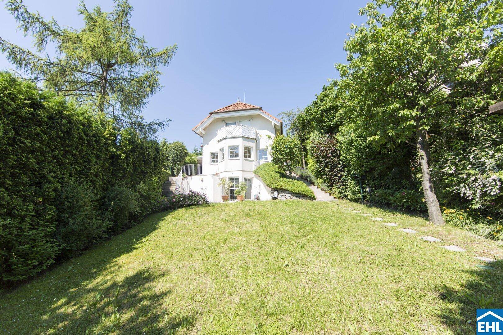 Hinteransicht des Hauses mit großem, leicht abfallendem Garten und üppiger Bepflanzung.