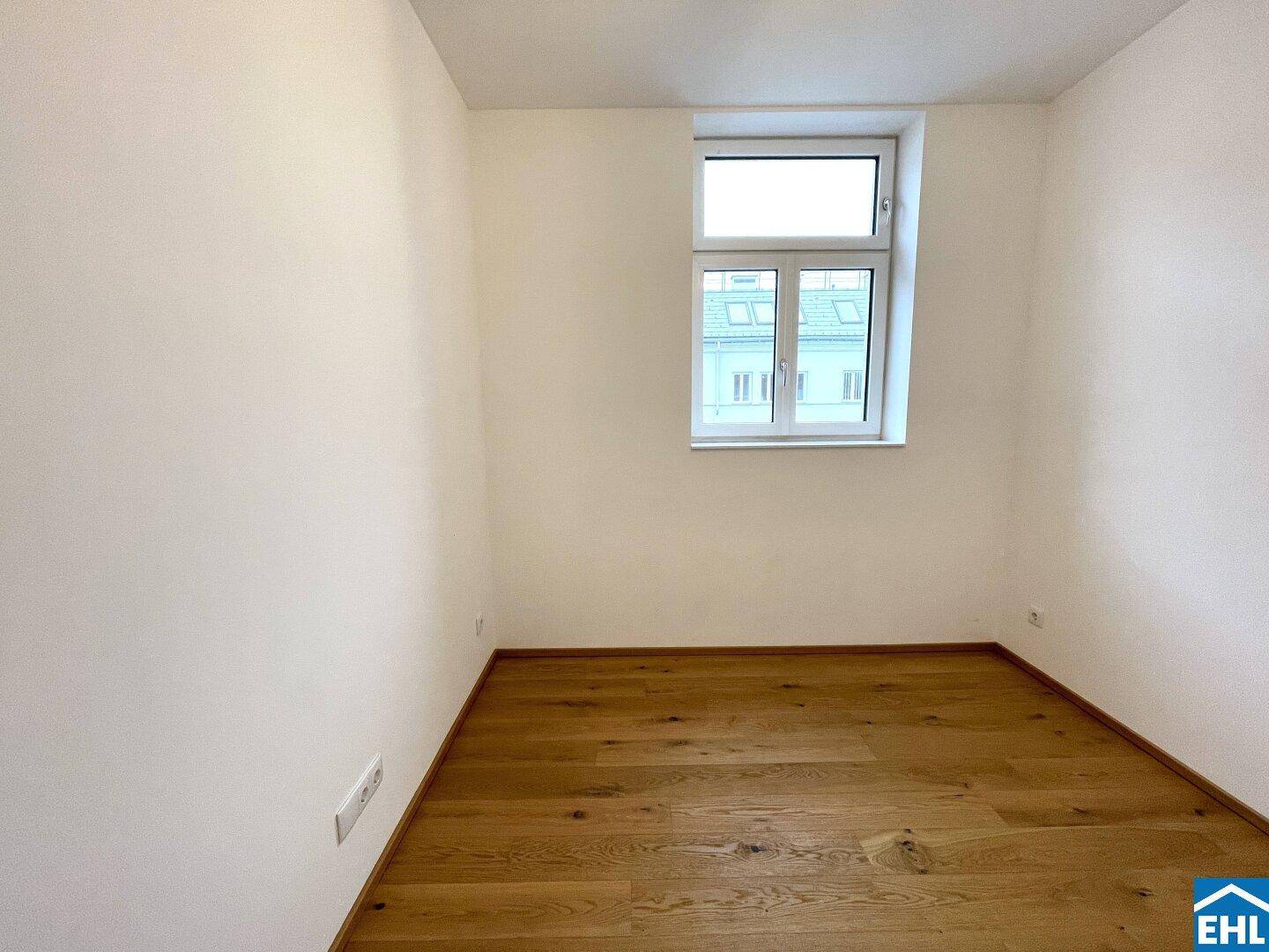 Freundlicher Raum mit einem Fenster und warmem Holzboden, vielseitig nutzbar als Schlaf- oder Arbeitszimmer.