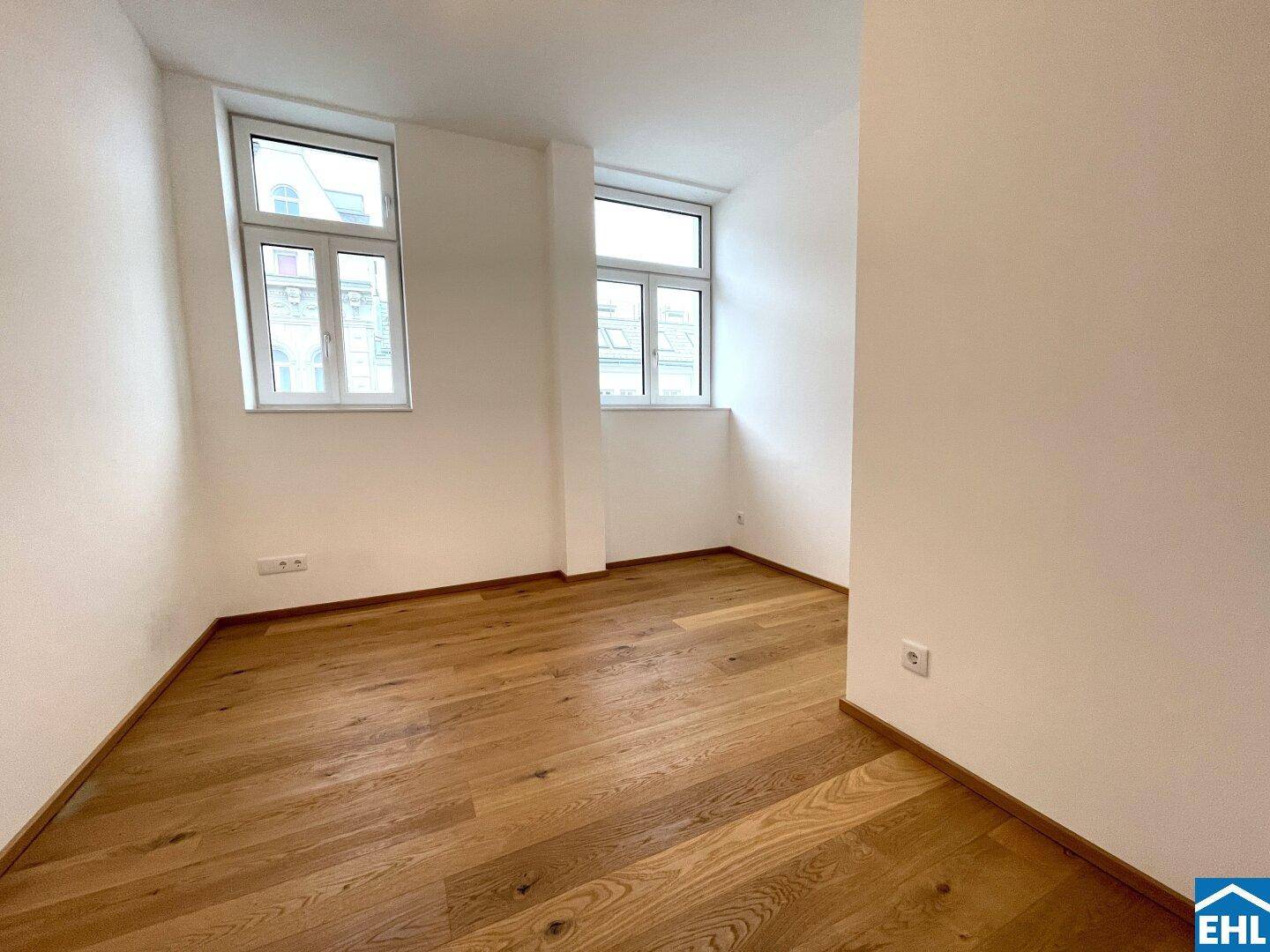 Heller Raum mit zwei Fenstern und schönem Holzparkettboden, ideal als Wohn- oder Schlafzimmer.