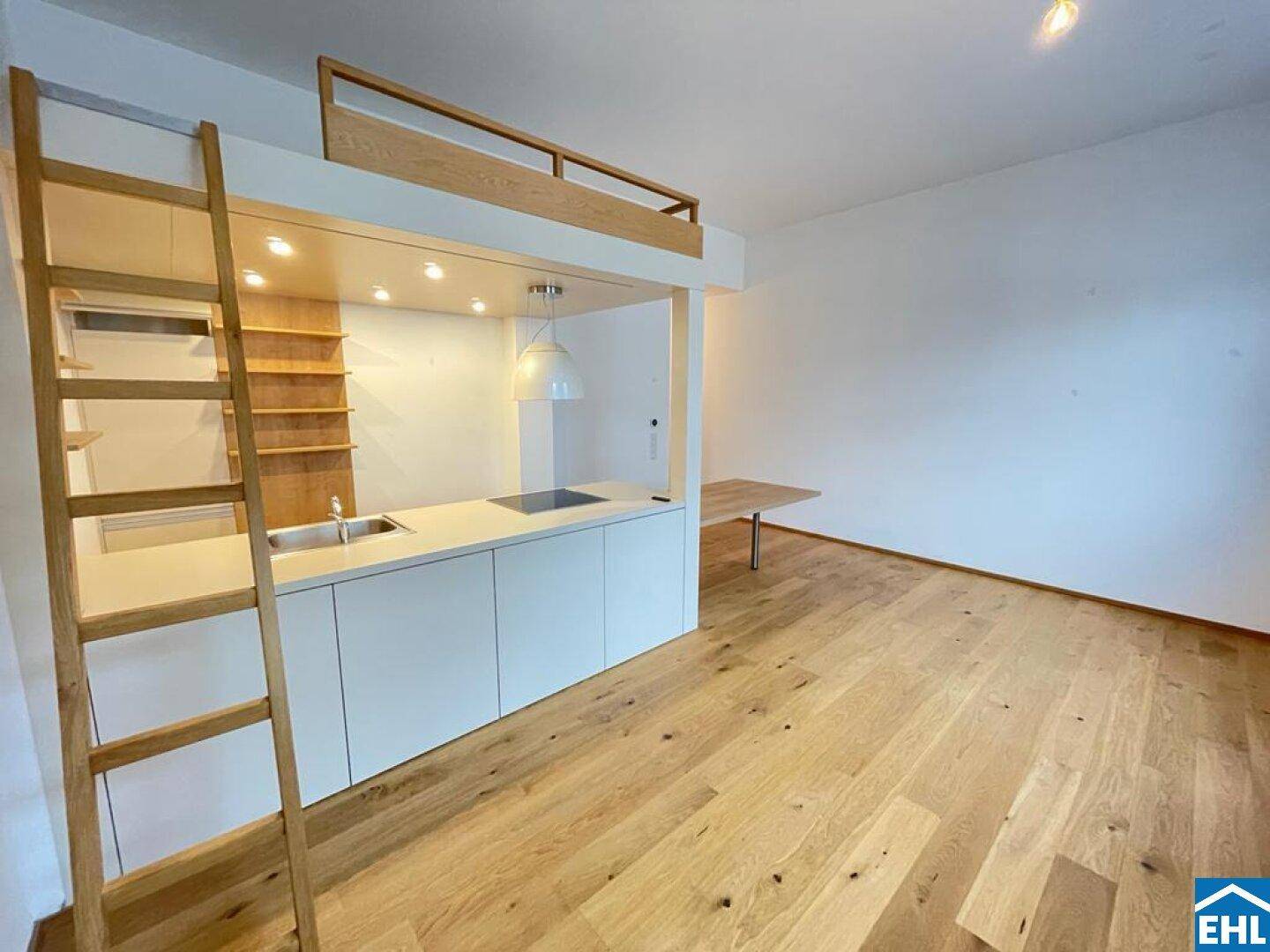 Moderne Küchenzeile mit integriertem Essbereich und Zugang zum Hochbett über eine Holzleiter.