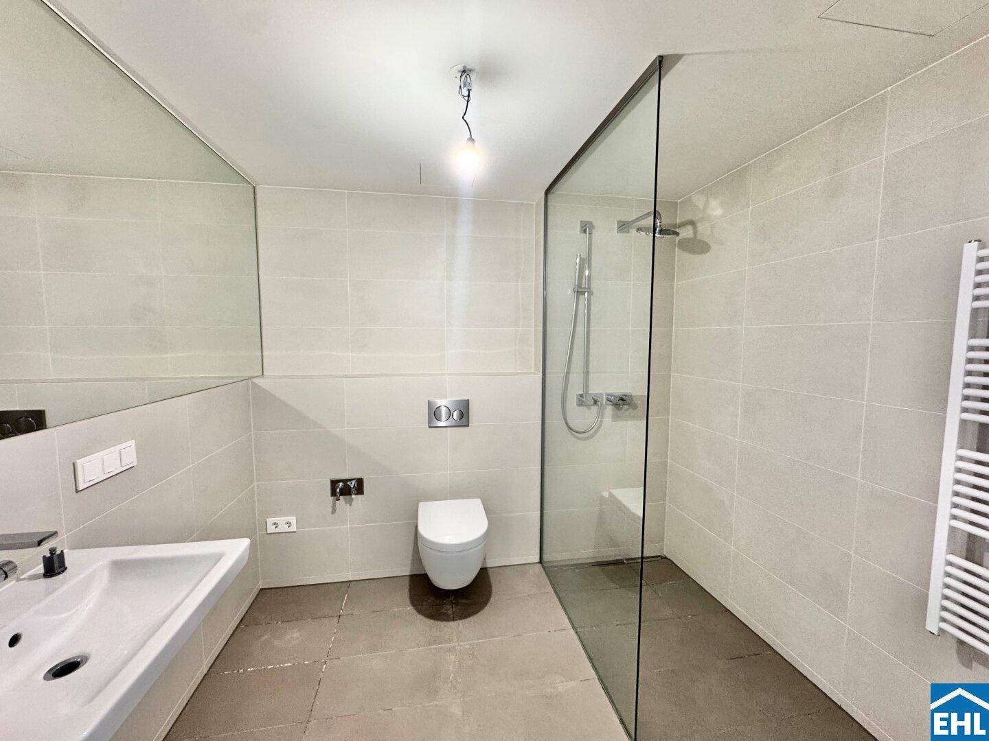 Modernes Badezimmer mit begehbarer Dusche, Wand-WC und großformatigen Fliesen.