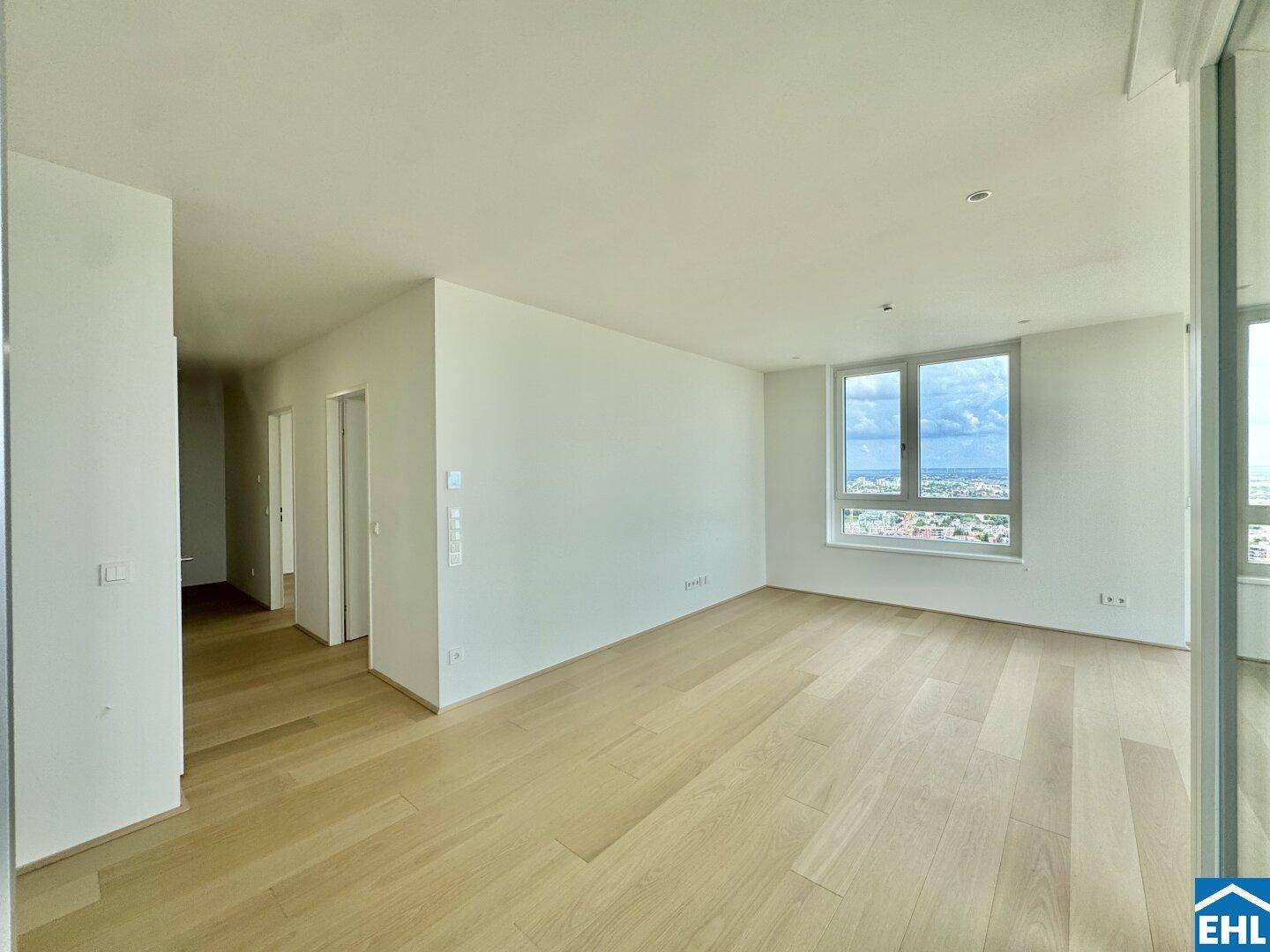 Heller Wohnbereich mit Holzboden und einem Fenster, das einen Blick auf die Umgebung bietet.
