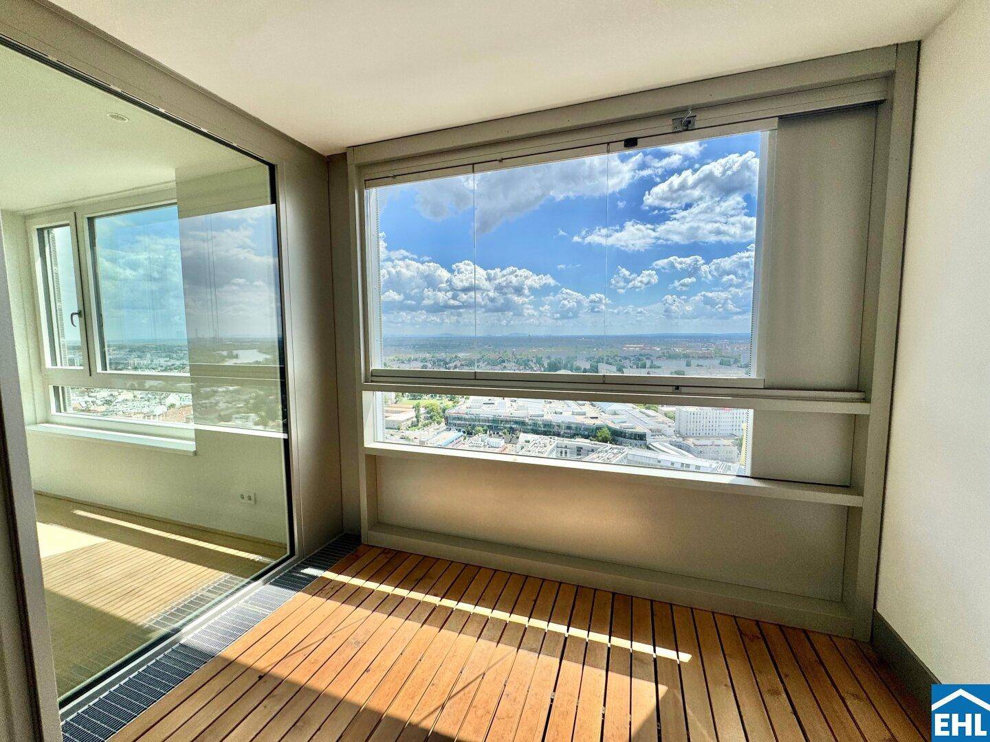 Verglaste Loggia mit Holzdeck und weitem Blick über die Stadt und die umliegende Landschaft.